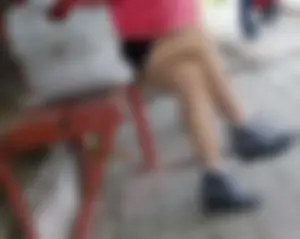 Girl in Short Skirt and Warm Pantyhose Sitting on a Bus Stop Cross-Legged