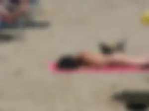 Brunette lady topless and in a black thong on the beach