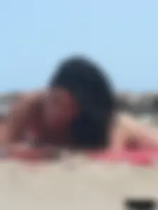 Brunette lady topless and in a black thong on the beach