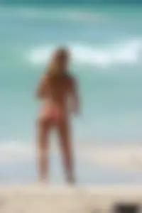 Topless girl in a tiny thong on the beach playing paddle ball