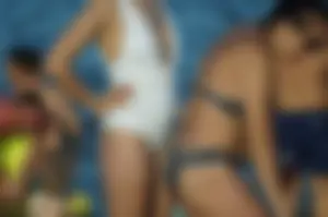 Girl in Sunglasses and a White One Piece Swimsuin Standing on Sand Beach Creepshots
