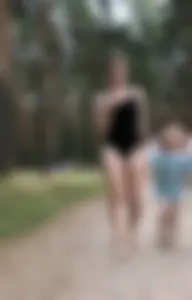 Cute Barefoot Girl in a Black Body Swimsuit Walking on a Road