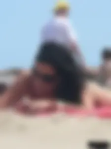 Brunette lady topless and in a black thong on the beach