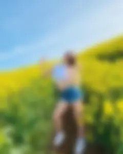 Smiling non-candid cutie wearing denim shorts in the middle of a field of flowers
