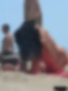Brunette lady topless and in a black thong on the beach