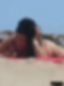 Brunette lady topless and in a black thong on the beach