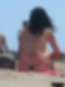 Brunette lady topless and in a black thong on the beach