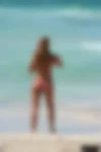 Topless girl in a tiny thong on the beach playing paddle ball