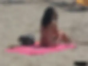 Brunette lady topless and in a black thong on the beach