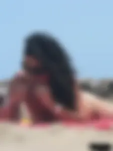 Brunette lady topless and in a black thong on the beach