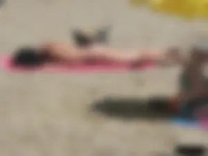 Brunette lady topless and in a black thong on the beach
