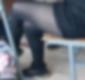 College teen girl's crossed legs in black pantyhose closeup creepshot: sitting at her desk in a classroom, wearing a short skirt and sneakers