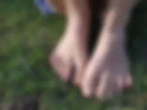 Candid girl with hot legs chilling on the grass in a park and showing off her feet