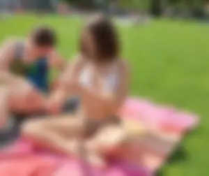 Young Candid Girl in a Swimsuit Sitting With Crossed Legs on the Grass at the Beach Creepshots