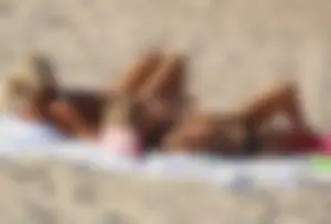 Topless mom and daughter on the beach getting some sun