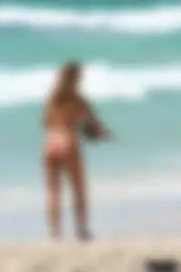 Topless girl in a tiny thong on the beach playing paddle ball