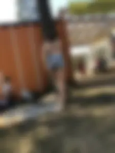 Young Skinny Girl Taking Off Her Denim Shorts Leaving a Swimsuit - Bending Over While Laying a Blanket on the Ground at a Lake Nature Park Gallery