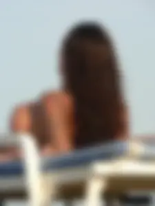 Topless tattooed lady on the beach with fake big tits