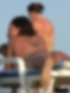 Topless tattooed lady on the beach with fake big tits