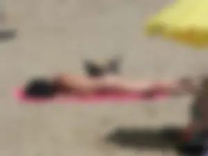 Brunette lady topless and in a black thong on the beach