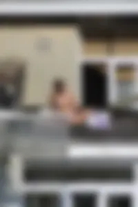 Neighbor on rooftop tanning in bikinis
