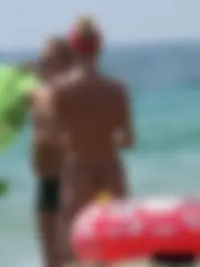 Topless skinny blonde lady in a g-string bikini at the beach