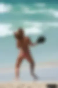 Topless girl in a tiny thong on the beach playing paddle ball