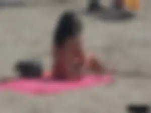 Brunette lady topless and in a black thong on the beach