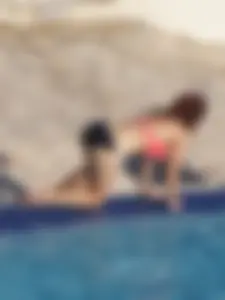 Sexy red haired girl in pink and black bikini at the pool