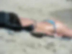 Brunette looking sexy on the beach in a blue thong bikini