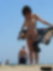 Topless beach milf looking sexy in a tiny g-string bikini