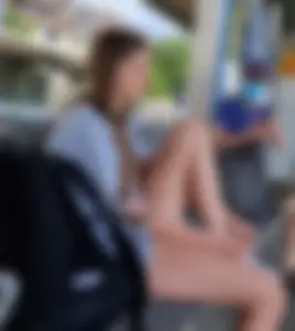 Candid Girl With Nice Long Legs in Mini Shorts Sitting at the Bus Stop And Tying Her Shoelaces