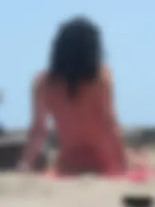 Brunette lady topless and in a black thong on the beach