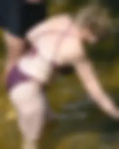 Chunky blonde enjoying some drinks in the water in her purple bikini