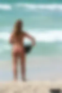Topless girl in a tiny thong on the beach playing paddle ball
