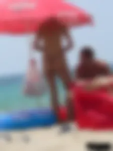 Topless skinny blonde lady in a g-string bikini at the beach
