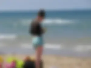 Sexy Girl in Shorts and a Lacey Blouse Standing on the Surf at the Beach Candid Photo