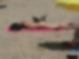Brunette lady topless and in a black thong on the beach