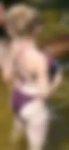Chunky blonde enjoying some drinks in the water in her purple bikini