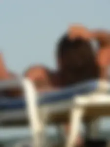 Topless tattooed lady on the beach with fake big tits
