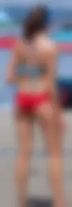 Skinny mature lady in red bikini bottom on the beach playing volleyball