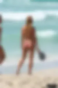Topless girl in a tiny thong on the beach playing paddle ball