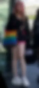 Awesome teen girl with pink dyed hair in hosrts sitting on the ground at the bus stop