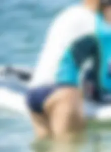 Girl in the water in a navy blue bikini bottom, shirt and hat with a nice ass