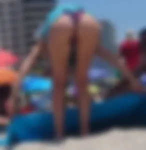 Sexy milf at the beach in a colorful semi thong bikini