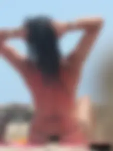 Brunette lady topless and in a black thong on the beach