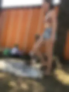 Young Skinny Girl Taking Off Her Denim Shorts Leaving a Swimsuit - Bending Over While Laying a Blanket on the Ground at a Lake Nature Park Gallery