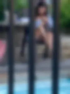Girl in Panties and a Shirt Sitting With Bent Legs by the Pool
