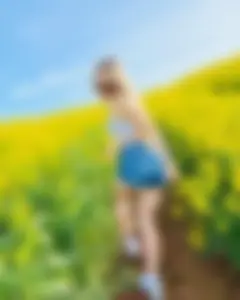 Smiling non-candid cutie wearing denim shorts in the middle of a field of flowers