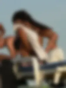 Topless tattooed lady on the beach with fake big tits